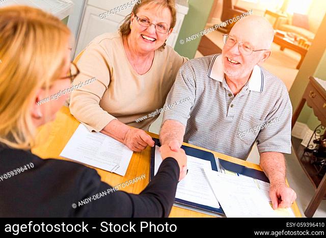 Senior Adult Couple Going Over Documents in Their Home with Agent At Signing