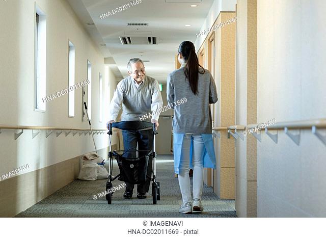 Senior man using mobility walker and care worker