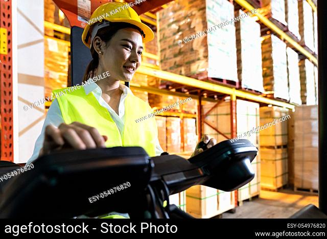 Portrait asian female warehouse worker using forklift truckin large warehouse distribution center. Business warehouse storage transportation and logistic...