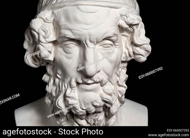 White gypsum copy of ancient statue of Homer head for artists isolated on a black background. Plaster sculpture of man face
