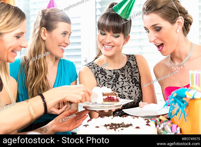 Four beautiful women and best friends smiling while sharing a tasty birthday cake during surprise anniversary at home