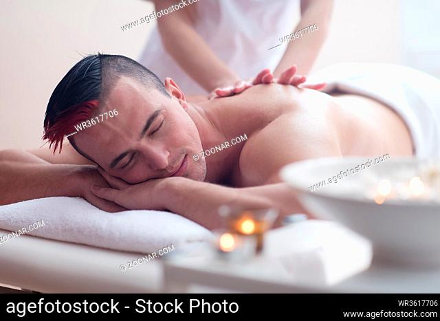 Positive young man having a back massage in a spa center