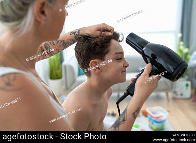 Close-up of pregnant hairdresser drying boy's hair at home