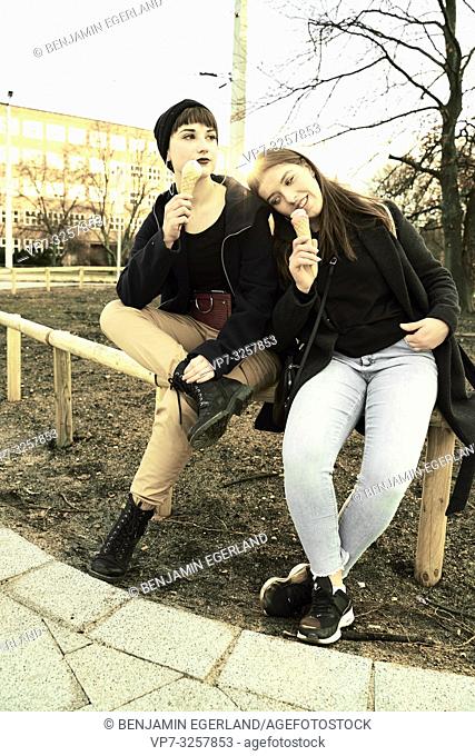 two women sitting together in city with ice cream cones, warm winter day, in city Cottbus, Brandenburg, Germany
