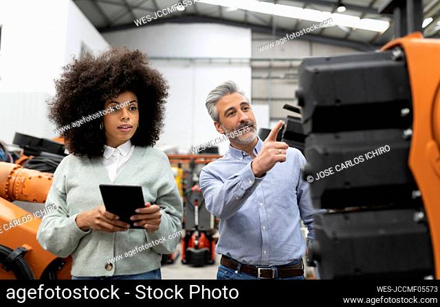 Developer showing machine to technician in factory