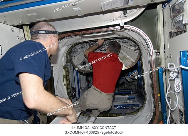 NASA astronaut Dan Burbank, Expedition 30 commander, closes a hatch in the International Space Station as crew members prepare to move to the appropriate Soyuz...