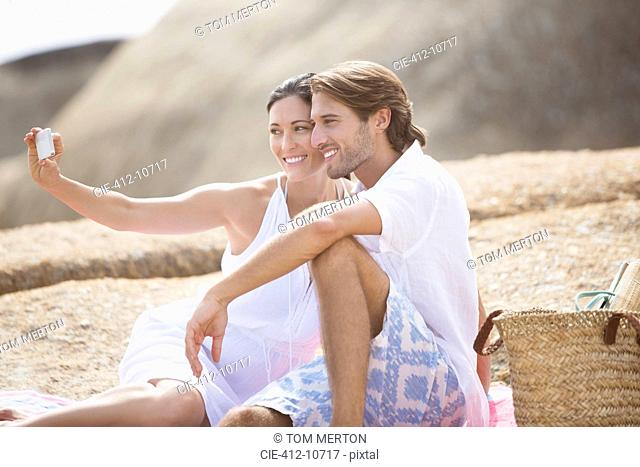 Couple taking pictures together on sandy beach