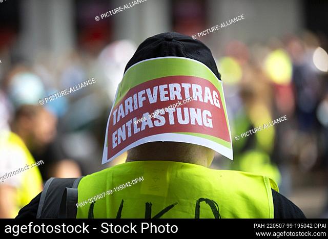 07 May 2022, North Rhine-Westphalia, Duesseldorf: A demonstrator wears a headgear to which a piece of paper with the inscription ""Tarifvertrag Entlastung""...