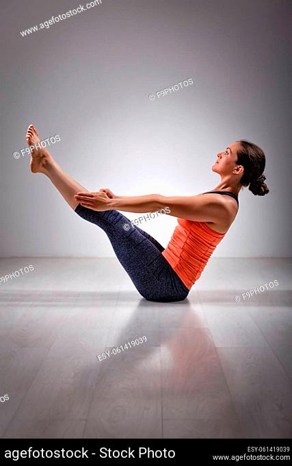 Beautiful sporty fit yogini woman practices yoga asana Paripurna navasana - boat pose