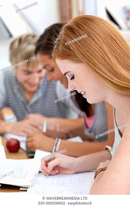 Teen girl studying in the library with her friends Concept of education