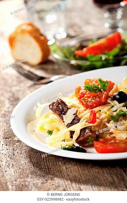 frische Pasta mit Tomaten und Oliven auf einem Teller