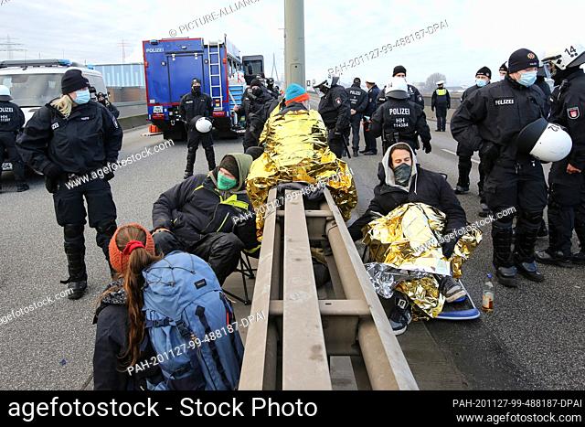 27 November 2020, Hamburg: Policemen stand behind activists who have chained themselves with steel pipes on the Köhlbrandbrücke in the port of Hamburg