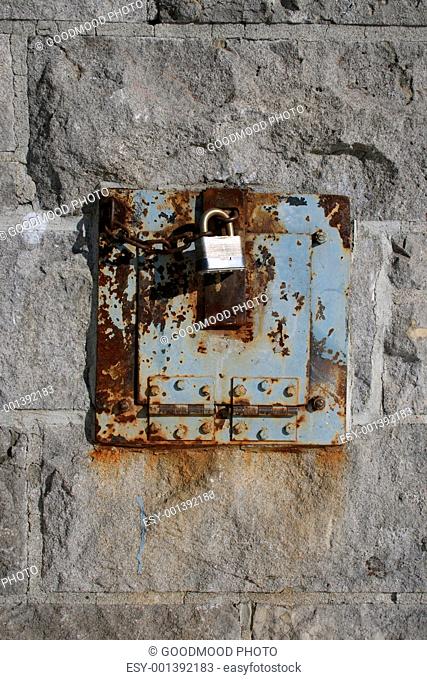 Iron lock and rusty chain on a stone wall