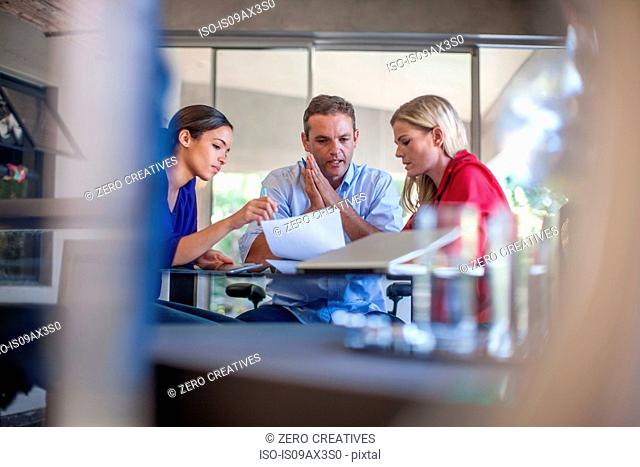 Three designers meeting at conference table in design office