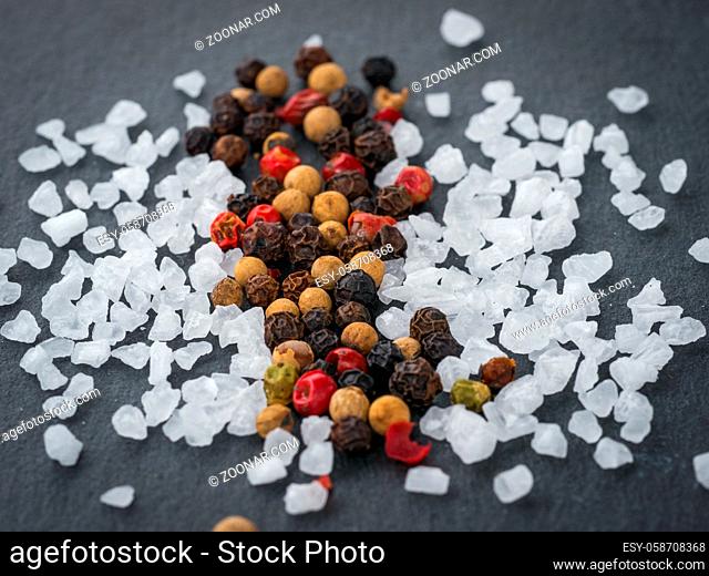 Coarse sea salt and peppercorns on slate background.Close up. Food background