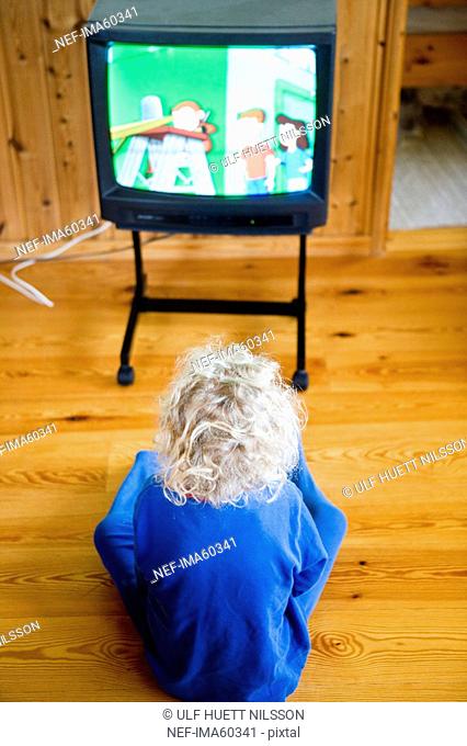 A girl sitting on the floor watching TV