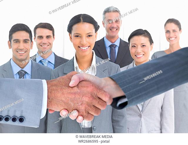 Handshake in front of business people in office against white background