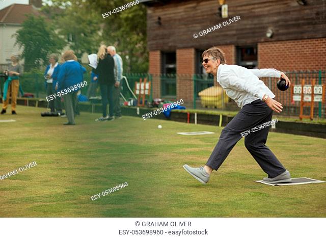 A side view shot of an excited senior woman taking her shot in a game of lawn bowling