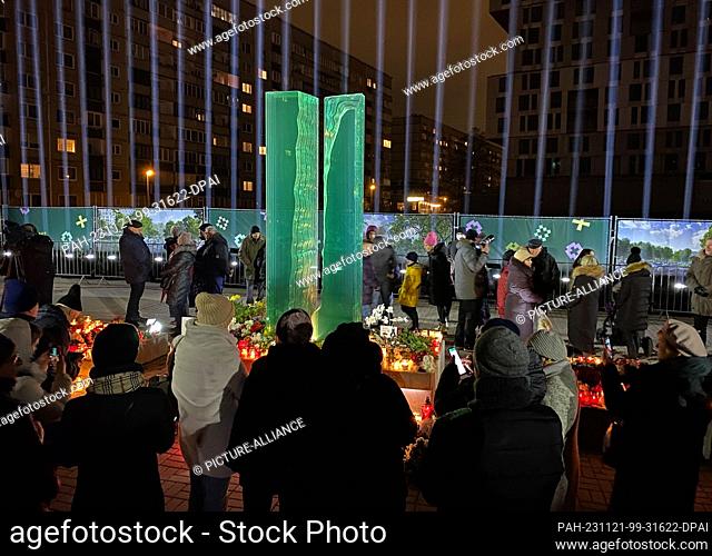 21 November 2023, Latvia, Riga: People stand at the memorial for the victims of the Riga collapse tragedy. Ten years after the collapse of a supermarket roof in...