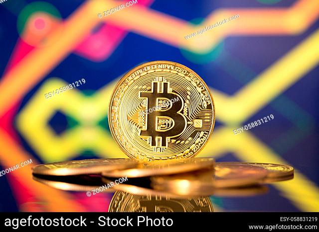 Golden bitcoin are stacked on a bright background of business graphs close-up. Bitcoin cryptocurrency