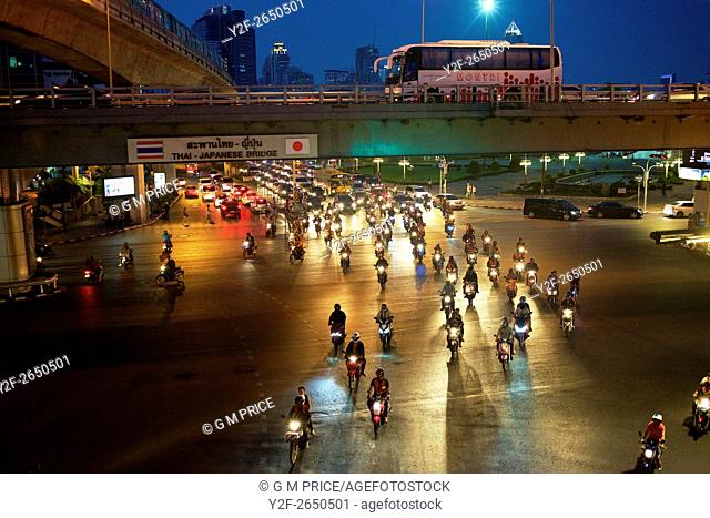 pack of motorcycles crosses intersection on Rama IV road at dusk, Bangkok