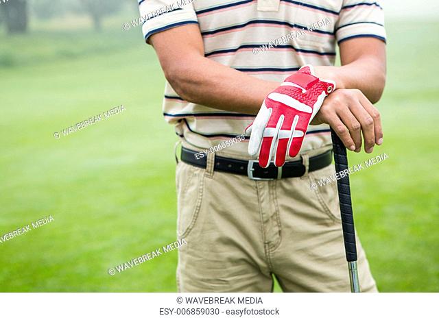 Golfer standing and leaning on his club
