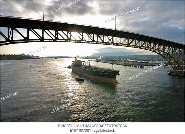Canada, BC, Vancouver  Freighter is escorted under the Second Narrows bridge on the Burrard Inlet by harbour tugs