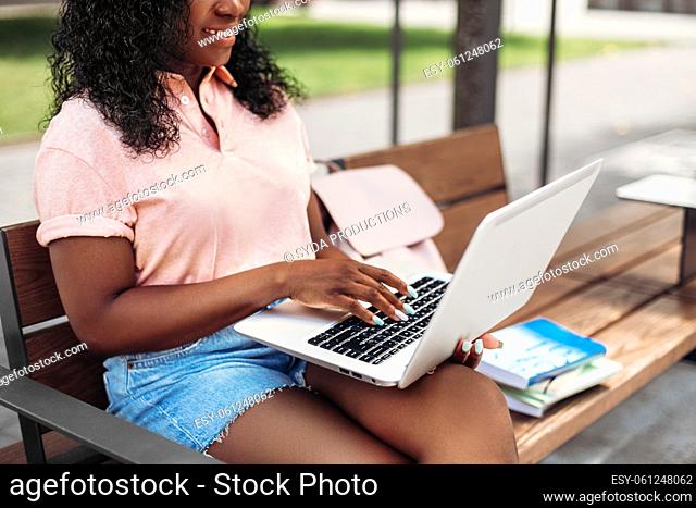 african student girl with laptop and books in city
