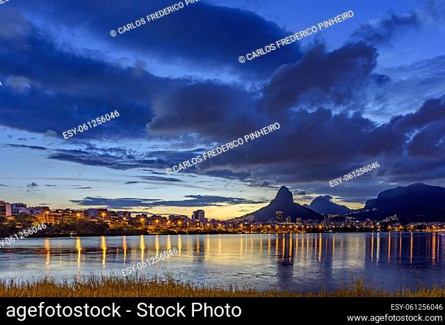 Dusk at Rodrigo de Freitas lagoon with the buildings, hills and lights of the city of Rio de Janeiro reflected in the water