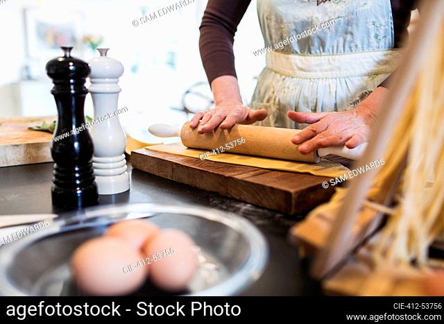 Woman rolling dough with rolling pin in kitchen