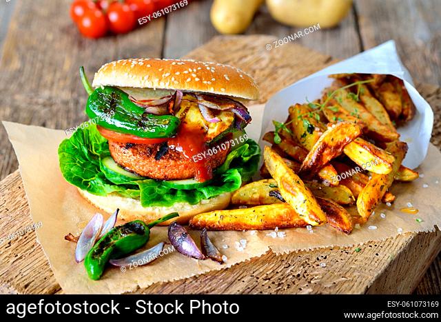 Veganer Burger mit Soja-Seitan-Patty und Grillgemüse mit Pimientos dazu knusprige Pommes ? Meatless street food ? delicious veggie burger with soy patty and...