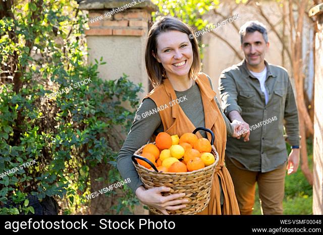 Happy couple holding a basket with lemons and oranges