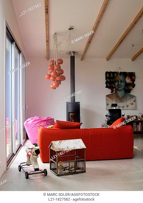 Lounge. Toy horse on wheels. Cage-shaped house. Red sofa. Wood stove. Dental chair. Oranges hanging lamps. Interior designed by Gabriel Rodriguez