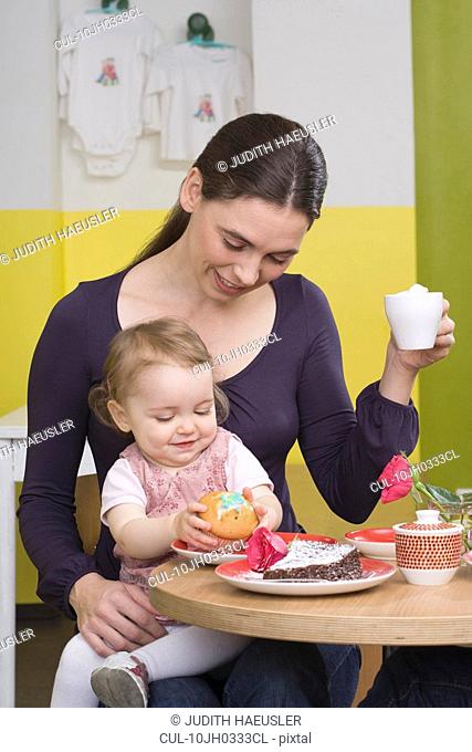 Young girl with cake, on mothers lap