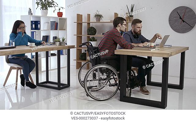 Hipster man in wheelchair working in office
