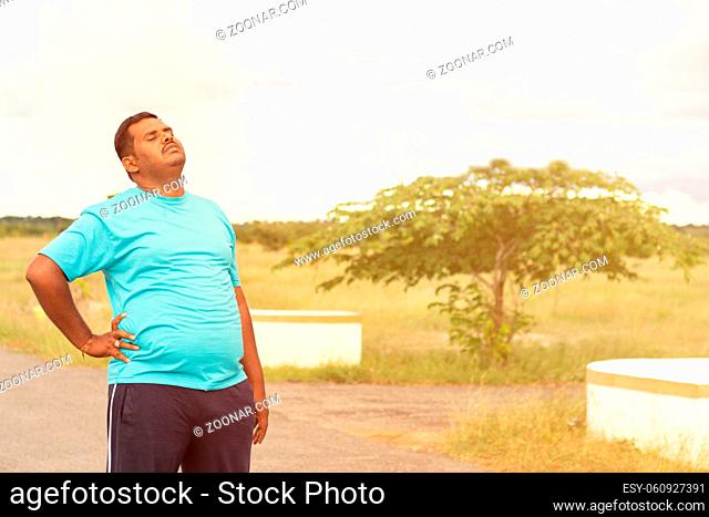 Tired young obese man holiding his back while jogging - Concept of fat man fitness and unhealthy lifestyle