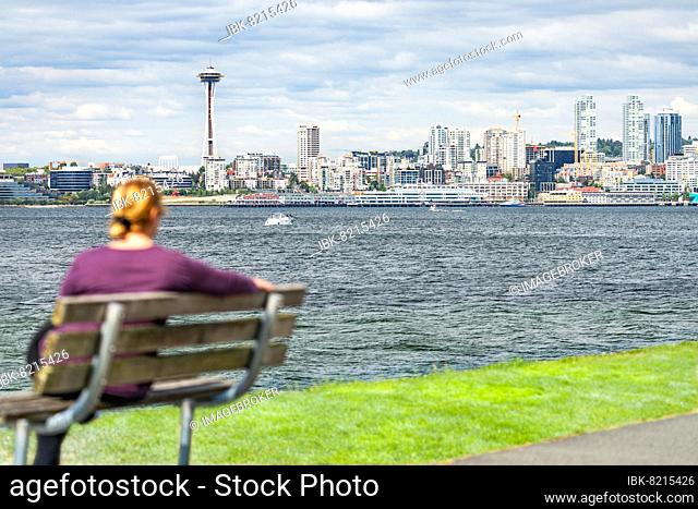 Woman sitting on bench looking at the seattle, washington skyline