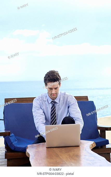 A businessman sitting on a sofa and looking at a computer