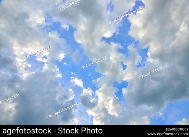 Blue sky background with fluffy cumulus white and gray clouds at sunlight backlit. Majestic heaven - meteorology or religious concept