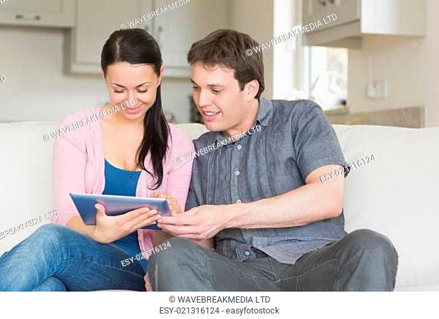 Couple sitting on the couch while using a tablet computer in the living room
