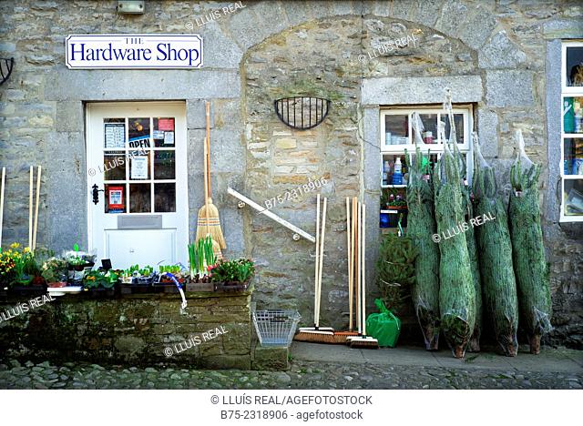 Close up of the front of a hardware store with Christmas trees, brooms and plants, in the village of Grassington. Yorkshire Dales, Englang, UK, Europe