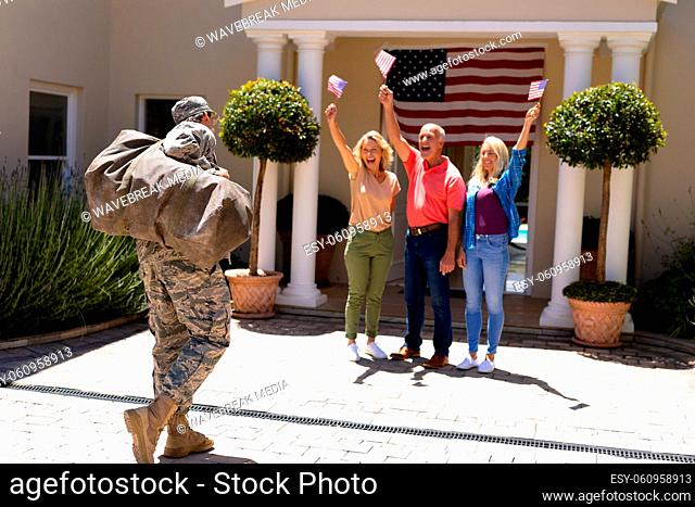Excited caucasian family with flags cheering military soldiers return home at the entrance