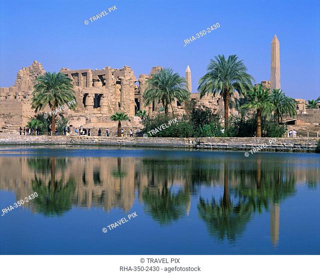 Reflections in the sacred lake of the temple, obelisks and palm trees at Karnak, near Luxor, Thebes, UNESCO World Heritage Site, Egypt, North Africa, Africa