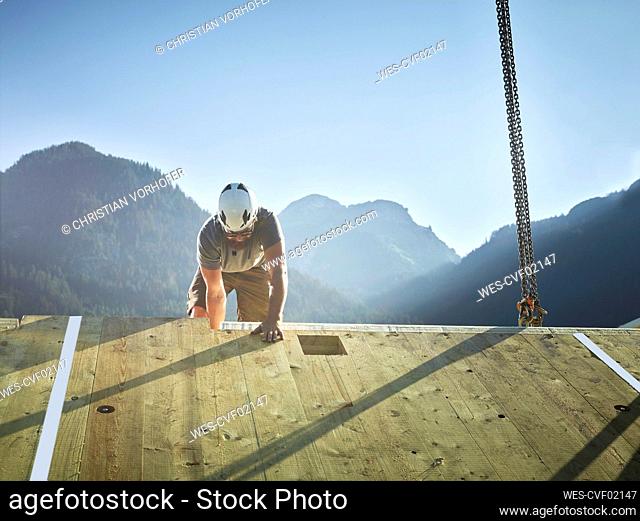 Carpenter working on roof in front of mountains