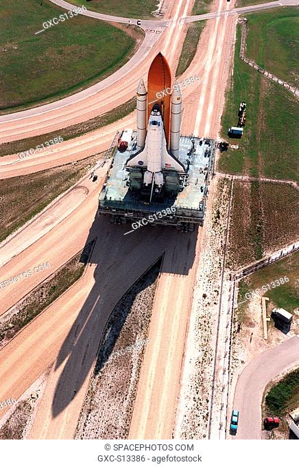 05/16/1999 -- Casting a giant shadow across the crawlerway, a crawler transporter slowly maneuvers Space Shuttle Discovery
