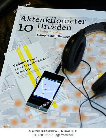 (ILLUSTRATION) A city map, headphones, a smartphone with GPS and an invitation for the new piece 'Radioortung - 10 Aktenkilometer Dresden' sit on a table during...