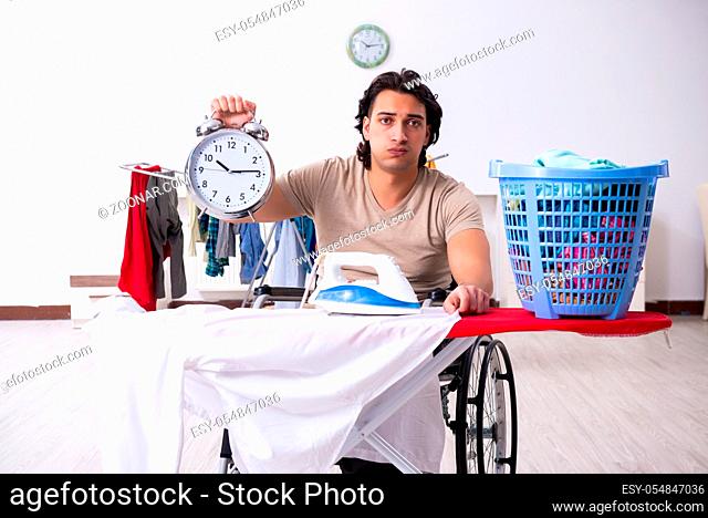 The young man in wheel-chair doing ironing at home
