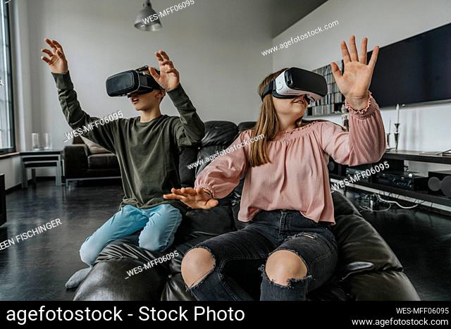 Friends looking through virtual reality simulators while relaxing on couch at home