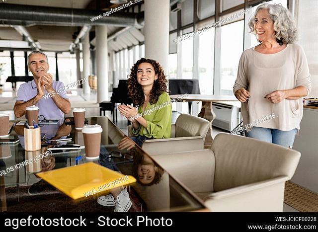 Happy businessman with colleagues clapping in office