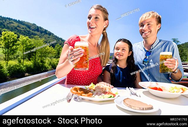 Happy family at lunch on river cruise with beer glasses on deck